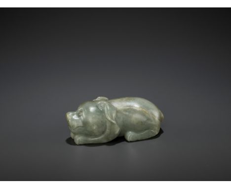 A CARVED CELADON AND RUSSET JADE FIGURE OF A DOG, LATE MING DYNASTYChina, 1368-1644. The recumbent dog finely carved with a c