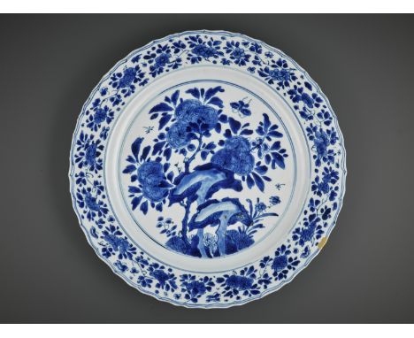 A LARGE BLUE AND WHITE ‘PRUNUS AND BUTTERFLY’ LOBED DISH, KANGXI MARK AND PERIODChina, 1662-1722. The shallow sides rising fr