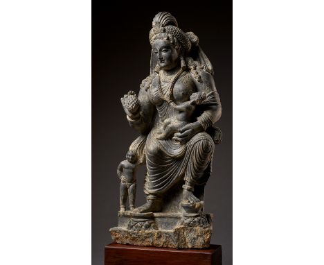 A HIGHLY IMPORTANT AND LARGE SCHIST STATUE OF HARITI, GANDHARA, 2ND-3RD CENTURYDepicted seated in European fashion with each 