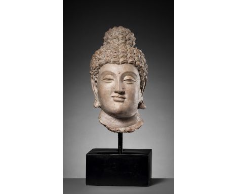 A RARE AND IMPORTANT TERRACOTTA HEAD OF BUDDHA SHAKYAMUNIAncient region of Gandhara, 4th century. The large head is superbly 