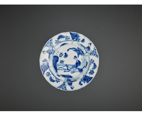 A BLUE AND WHITE ‘LADY IN A GARDEN’ LOBED DISH, KANGXI MARK AND PERIODChina, 1662-1722. The shallow sides rising from a short
