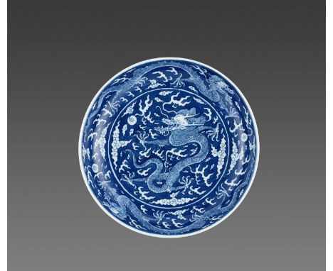 A BLUE AND WHITE REVERSE-DECORATED “DRAGON” DISH, DAOGUANG MARK AND PERIODChina, 1821-1850. The shallow dish with rounded sid