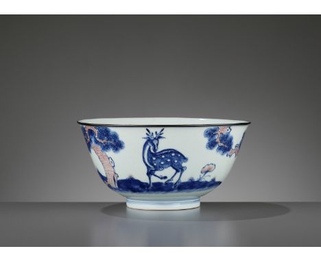 A COPPER-RED-DECORATED BLUE AND WHITE ‘DEER’ BOWL, QIANLONG MARK AND PERIODChina, 1735-1796. The deep rounded sides rising to