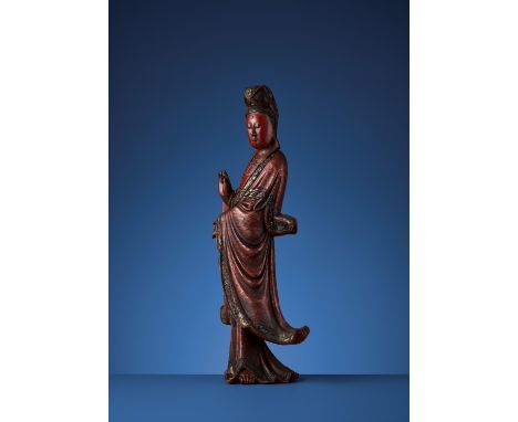 A VIETNAMESE RED AND GILT-LACQUERED WOOD STATUE OF GUANYINVietnam, 19th century. Carved standing with the right hand raised a