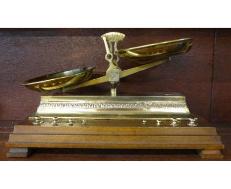 A pair of brass scales with weights mounted on a wooden base, width of base 34.5cm