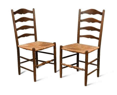 Edward Gardiner, a pair of stained ash ladder back chairs, circa 1920, the shaped ladder backs above rush seats, stamped Ed G