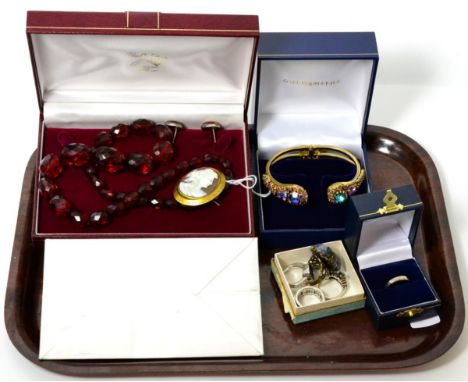 A faceted bakelite bead necklace, a shell cameo brooch in a gilt metal frame, a pair of amber stud earrings, a hinged bangle 