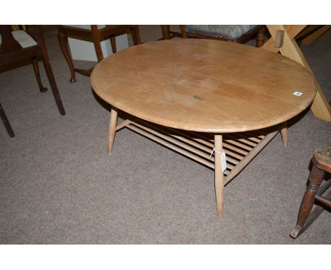 A large oval light elm Ercol coffee table, raised on splayed turned legs joined by an undertier of turned spindles (top in ne