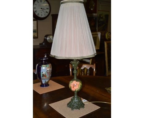 An unusual table lamp with tall tapering pleated shade with wavy bottom rim, on green painted base with a Moorcroft style glo