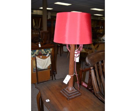 A mahogany Corinthian column pattern table lamp with circular red tapering shade.