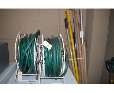 A large bundle of miscellaneous garden tools; and two hose pipes on reels.