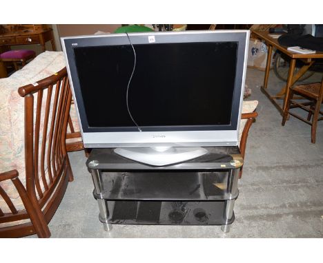A Panasonic Viera flat screen TV in silver coloured surround; together with a three-tier black glass TV stand.