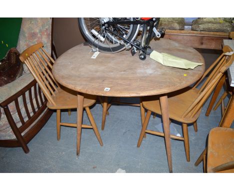 An Ercol circular light coloured elm dining table with splayed slender turned legs; and a set of four solid seat dining chair