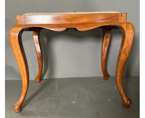 A wooden framed piano stool with a scrolling upholstered seat 