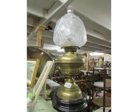 A brass oil lamp with shade and chimney.