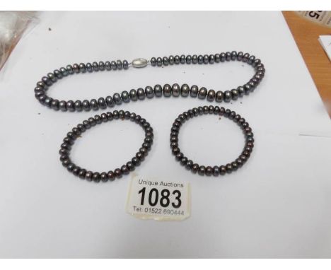 A black Honora graduated pearl necklace and 2 matching bracelets.