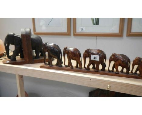 A pair of elephant book ends (trunk a/f) and 6 graduated wooden elephants on stand.