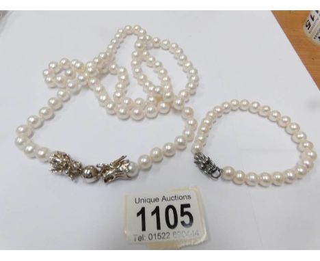 A white pearl necklace with silver dragon fastening (37" long) with a matching bracelet.