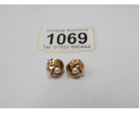 A pair of gold stud earrings set with a pearl.