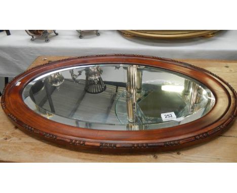 An oval framed bevel edged mirror.