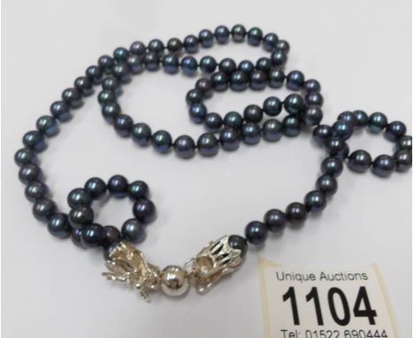 A black (navy?) pearl necklace with silver dragon fastening (37" long).