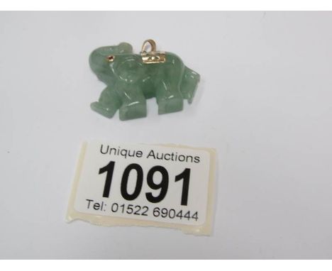 A jade elephant pendant with gold trim and ruby eye.
