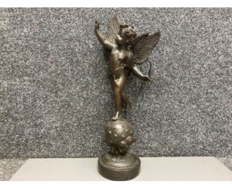A bronzed metal sculpture of Cupid standing on a globe 45cm high