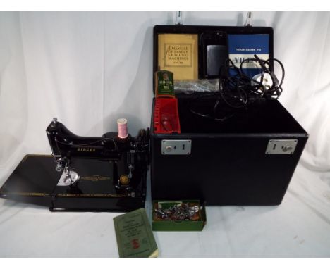 An electric Singer sewing machine with manual and hard travel case