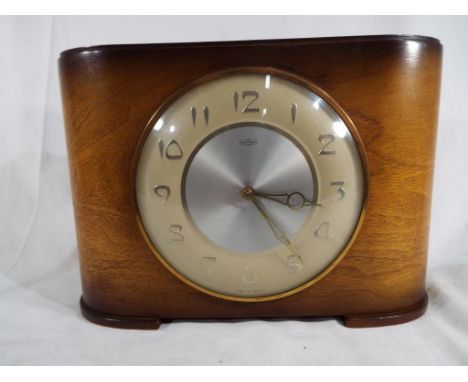 A ‘Time Savings’ mantel clock, coin operated/ wound mechanical clock Made in England in an Art Deco styled mahogany case, the