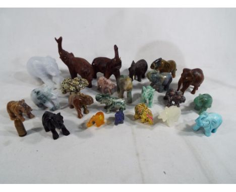 A collection of approximately 23 carved elephants to include wooden, hard stone, lapis lazuli, jade, amber and other