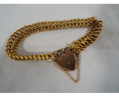 A yellow metal bracelet with padlock clasp and safety chain, the padlock and chain stamped 9C, approx weight 16.10 gm - Est £