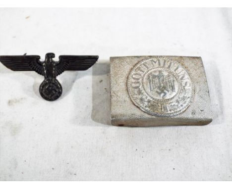 A World War Two (WW2) German Heer pebbled aluminum Belt Buckle and an Army Visor Hat badge with Eagle, Swastika and Wreath In