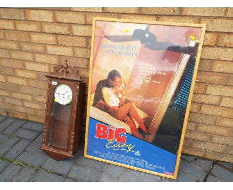 A modern Hermle wall clock with pendulum and key and a promotional poster entitled The Big easy depicting Dennis Quaid and El