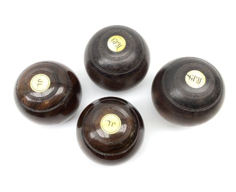 Four early 20th century lawn bowl balls, to include a pair with inset initialled ivory roundels, and mother of pearl roundels