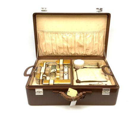 An early 20th century guilloche enamel worked vanity set, in case, complete in the brown travel suitcase. The set comprising 