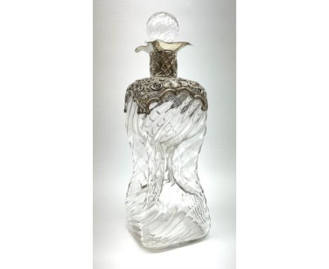 An Edwardian silver mounted glass glug glug decanter, of wrythen twist form with pierced and scrolling silver mounted to shou