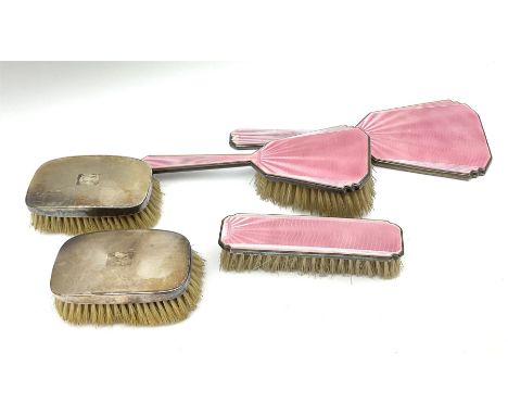 A silver and pink guilloche enamel dressing table set, comprising hand held mirror, hair brush and clothes brush, hallmarked 