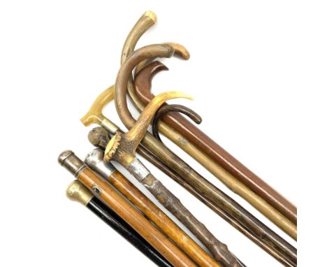 Collection of wooden walking sticks and canes, including horn handled stick with silver collar, three metal topped canes, fiv