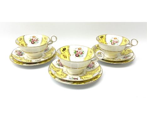 A set of three Fenton teacups, saucers and plates, decorated with floral sprays and yellow panels, heightened throughout in g