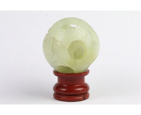 Jade Puzzle Ball carved with a fish design comprising three layers plus a central ball, 6cm wide, on stand 