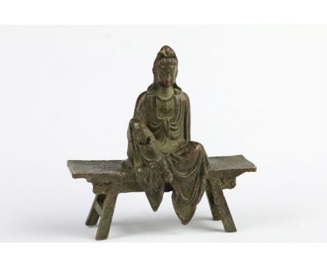 Cast bronze Guanyin Buddha figurine modelled seated on a bench. Measures 8.5cm tall. 
