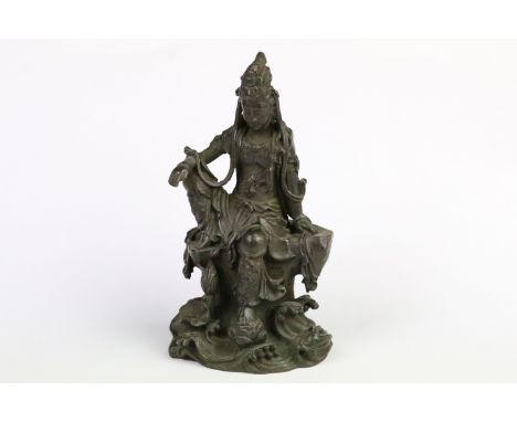 Cast bronze figurine in the form of Guanyin seated on a rock. Measures 11.5cm tall. 