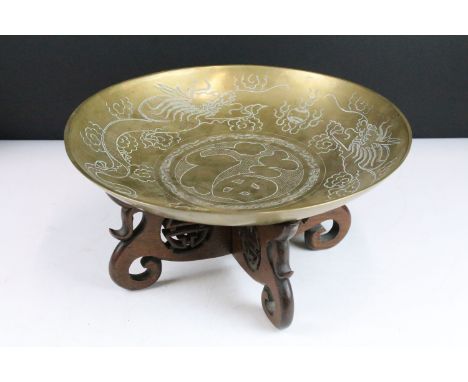 Large brass Chinese bowl with Chinese character symbols and dragon etching on carved wooden display stand. 16cm high, 36cm di