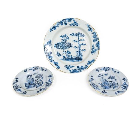 An English Delft Charger, 18th century, painted in blue with a large peony bloom beside bamboo shoots and a fence between, de
