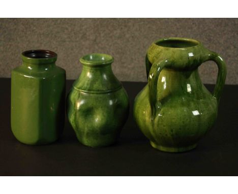 A collection of three green glazed ceramic vases. Two Arts and Crafts green glaze pieces one with a pinched design and the ot