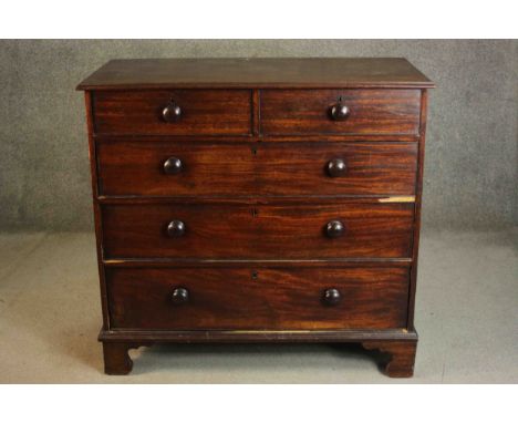 A Victorian mahogany chest of two short over three long graduated cockbeaded drawers with turned handles on shaped bracket fe