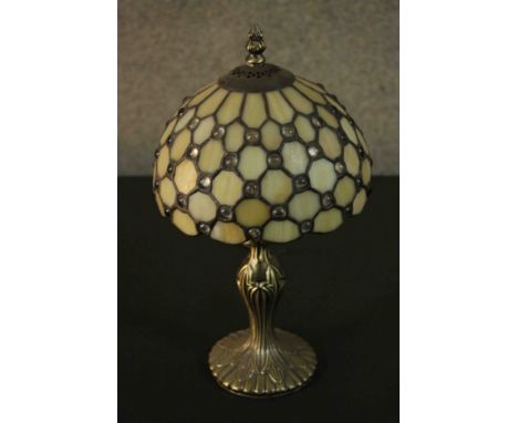 A Tiffany style table lamp, with a leaded stained glass shade on a bronzed metal base. 