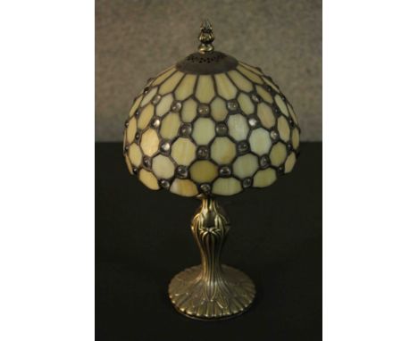 A Tiffany style table lamp, with a leaded stained glass shade on a bronzed metal base. 