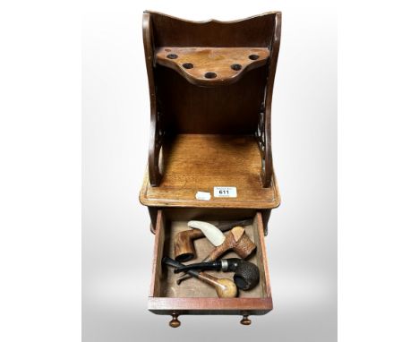 A mahogany pipe rack containing several pipes, width 23cm.