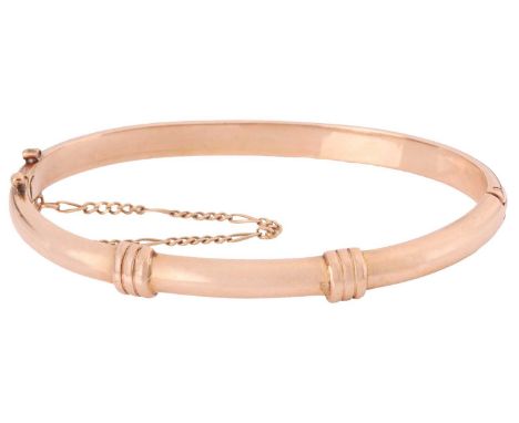 A hinged bangle, constructed in two curved halves adorned with fluted decorations, fastens with a concealed tension clasp wit